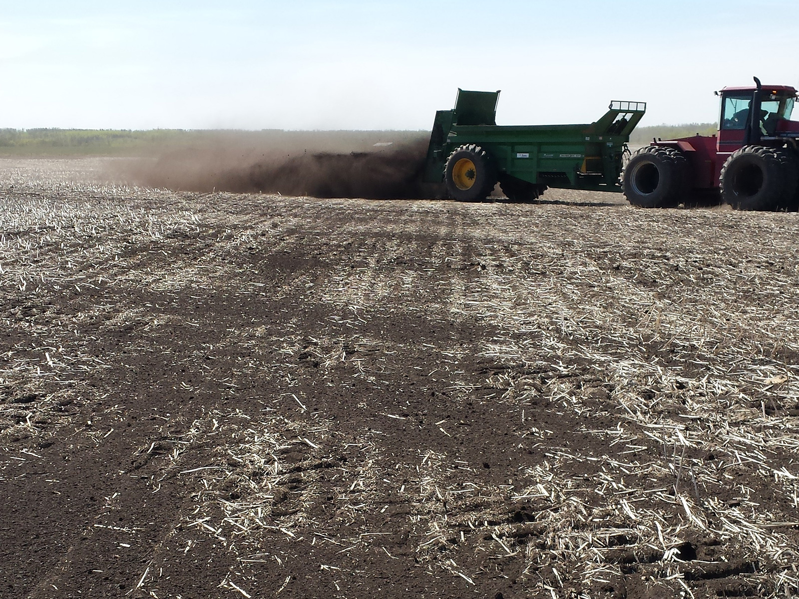 tractor spreading compost in field