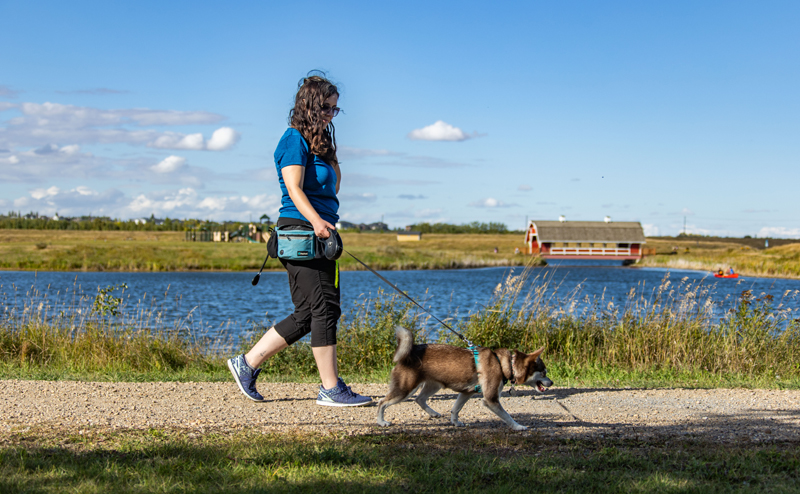 A woman walking a dog next to the water in Northeast River Valley Park